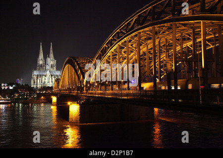 L'imponente cattedrale di Colonia durante la notte con il ponte di Hohenzollern in primo piano Foto Stock