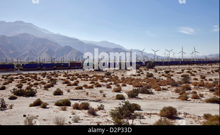 Wind Turbine di potenza appena fuori Palm Springs con un lungo treno merci passando attraverso il paesaggio in California, 2010 Foto Stock