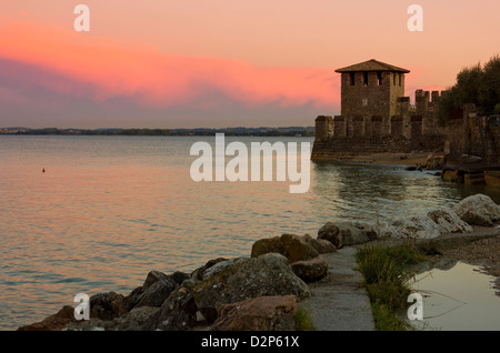 Lago di Garda vista in Sirmione, Italia con caldo tramonto rosso e la torre del castello scaligero nella distanza. Foto Stock