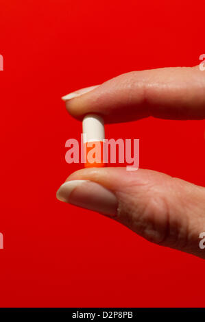 Illustrazione - Un foto illustrato mostra una donna tenendo un due-pillola colorata fra le dita di Dresda, in Germania, 27 gennaio 2013. Foto: Arno Burgi Foto Stock