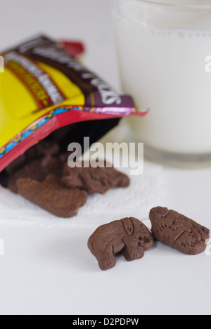 Al cioccolato a forma di animale i biscotti con un bicchiere di latte di mucca verticale con elephant e gorilla cookie fuoriuscita della confezione Foto Stock