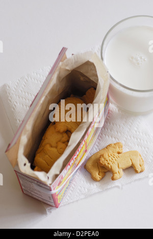 Animal crackers con un bicchiere di latte di mucca su un foglio di carta bianca igienico vista superiore con box Foto Stock