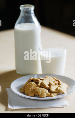 Crackers animale posto su una piastra bianca con bottiglia e bicchiere di latte di mucca Foto Stock