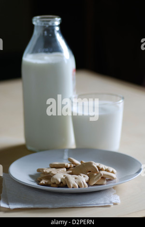 Crackers animale sulla piastra bianca con bottiglia di latte e un bicchiere di latte e igienico Foto Stock