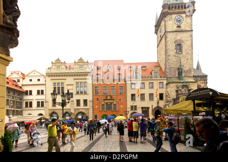 I turisti esplorano la vivace Piazza della città Vecchia di Praga, circondata da edifici colorati, l'Orologio Astronomico e lo storico Municipio della città Vecchia sotto An Foto Stock