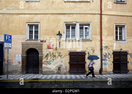 Un uomo stesso protegge dalla pioggia mentre si cammina attraverso la città di Praga Foto Stock