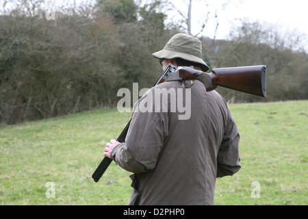 L uomo indossa abbigliamento caccia a piedi con un colpo di pistola sulla sua spalla. Foto Stock