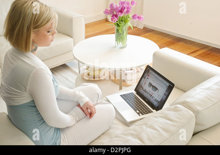 Amburgo, Germania, una giovane donna con un MacBook nel soggiorno Foto Stock