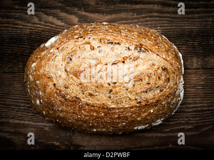 Artigiano della pagnotta di pane appena sfornato multigrain pane su sfondo di legno Foto Stock