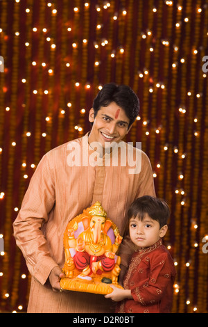 Padre e figlio tenendo un idolo del signore Ganesha Foto Stock