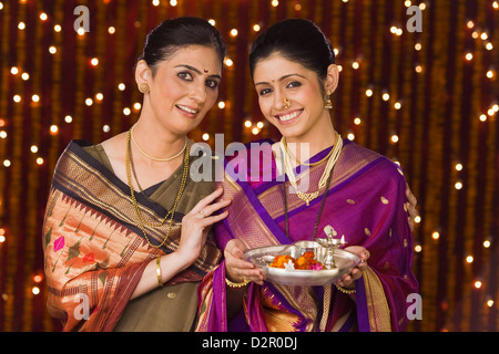 Le donne in possesso di un pooja thali e sorridente Foto Stock