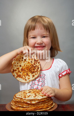 Il russo bambina mangia pancake con caviale rosso. Foto Stock