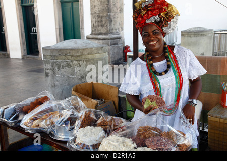 Bahiana donna nel tradizionale abito bianco la vendita di cibo di strada presso il quartiere Pelourinho, Salvador, Bahia, Brasile Foto Stock