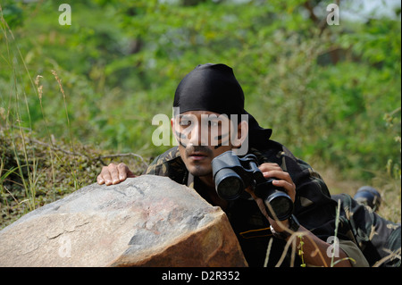 Soldato nascosto dietro una roccia con un binocolo Foto Stock