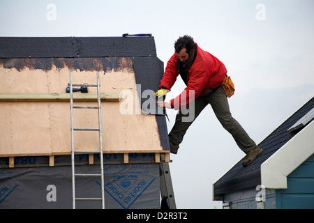 L'uomo il rifacimento dei tetti beach hut a testa Hengistbury, Dorset nel gennaio Foto Stock