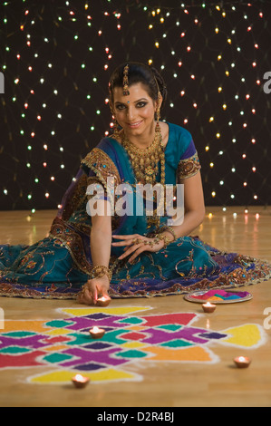 La donna la decorazione lampade a olio vicino rangoli a Diwali Festival Foto Stock