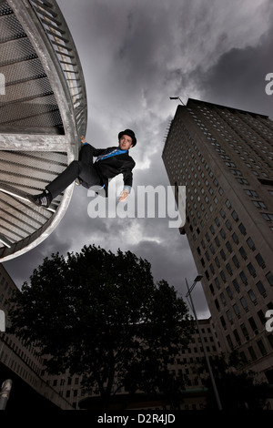 Parkour runner in tuta appesi da edifici aziendali Foto Stock