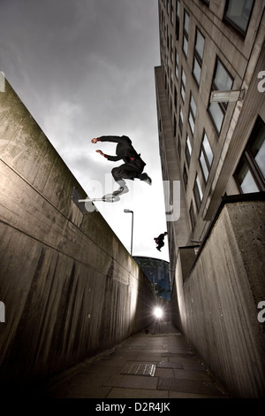 Parkour runner in giacca jumping vicolo urbano Foto Stock