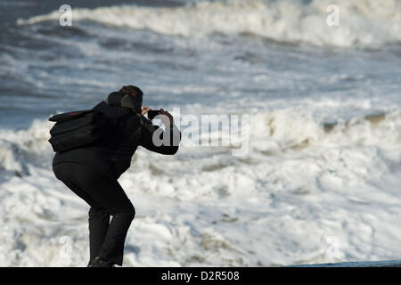 Aberystwyth Wales UK. Il 31 gennaio 2013 un uomo fotografie l'onda come gale force i venti e il mare in tempesta pastella il lungomare e la spiaggia a Aberystwyth sulla West Wales coast. Foto ©keith morris Foto Stock