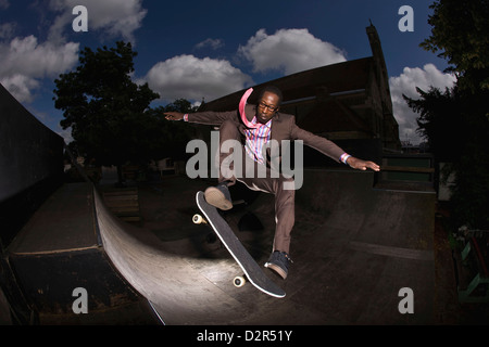 Guidatore di skateboard in tuta sulla rampa, metà azione aria stunt Foto Stock