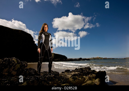 Surfista femmina in piedi in wetsuit a Waters Edge, sorridente