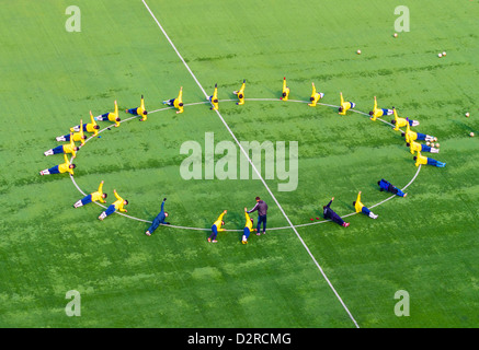 Team di giocatori di calcio di esercitarsi in il cerchio centrale del campo di calcio. Foto Stock