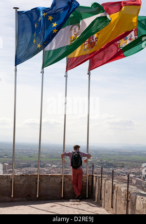 Un visitatore ammira viste da sotto bandiere sulla sommità della Torre de la Vela parte della vecchia Alcazaba nell'Alhambra Granada Spagna Foto Stock