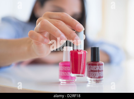 La donna caucasica selezionando una bottiglia di smalto per unghie Foto Stock