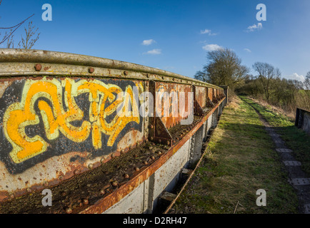 Coperto di graffiti in ghisa portante a ponte il sentiero pedonale lungo la vecchia linea ferroviaria in inverno, Warwickshire, Inghilterra, Regno Unito Foto Stock