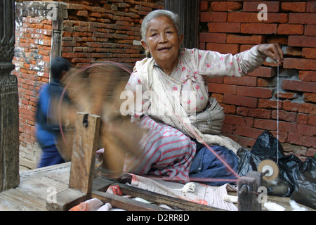 Una signora in Kathmandu la filatura della lana da utilizzare per realizzare i vestiti e gli indumenti. Foto Stock