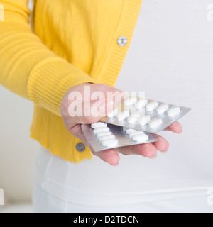 Supplementi materna. Asian donna incinta mano pillole / compresse medicina a casa. Foto Stock