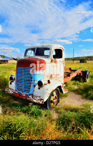 Vintage carrello abbandonato e ruggine lontano nel deserto, città fantasma in background Foto Stock