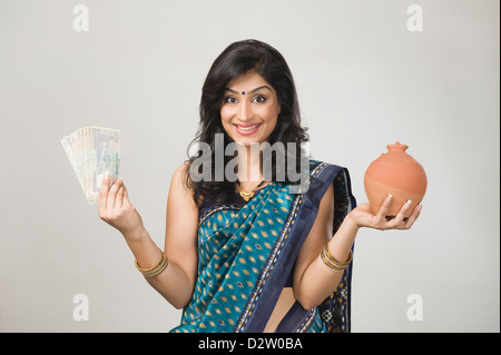 Ritratto di una donna detenere fondi e un piggybank Foto Stock