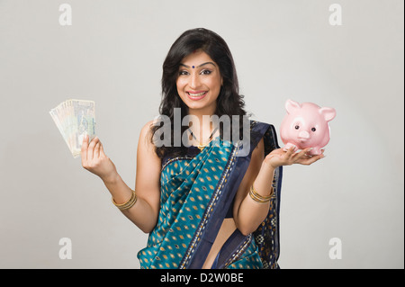 Ritratto di una donna detenere fondi e un piggybank Foto Stock