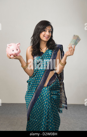 Ritratto di una donna detenere fondi e un piggybank Foto Stock