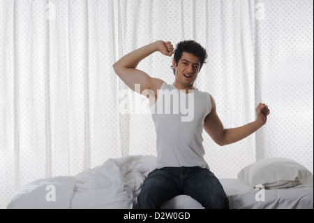 Uomo a sbadigliare e stretching sul letto Foto Stock