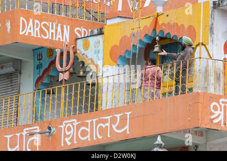 India, Rishikesh. Campane segnano l'ingresso a due santuari nella tera Manzil Tempio. Shiva è anche Trident presente. La religione sikh visitatore. Foto Stock