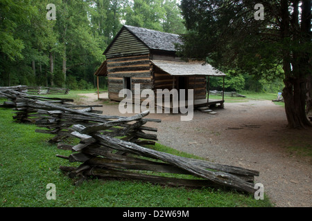 Rustici e vecchi log cabin, nei boschi con una rampa di split recinto accanto ad esso Foto Stock