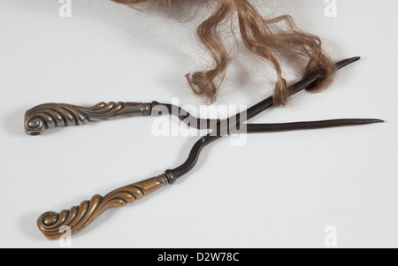 Un antico ferro arricciacapelli con i capelli Foto Stock