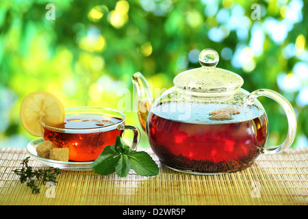 Tazza di tè e teiera su uno sfondo sfocato della natura. Foto Stock