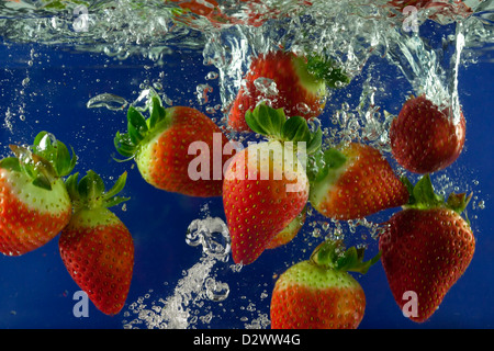 Strawberry splash in acqua con bolle contro sfondo blu Foto Stock