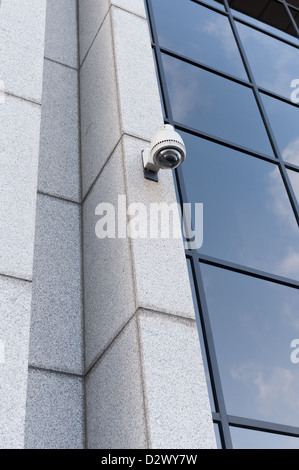 Sorveglianza con controllo remoto telecamera sulla faccia del moderno rivestito in marmo edilizia architettura con cielo riflettente nella finestra Foto Stock