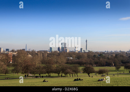 Le persone che si godono la soleggiata giornata di primavera in Primrose Hill, un parco con vista mozzafiato di tutta la città di Londra. Foto Stock