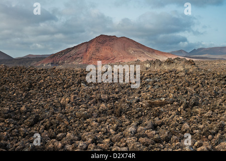 Aa campo di lava dalle eruzioni storiche a Lanzarote e Montana Bermeja, un cono vulcanico nel sud-ovest dell' isola Foto Stock