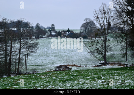 Farmland in inverno, prati coperti di neve, un flusso di fondo valle (Nord Mayenne, Paese della Loira, in Francia, in Europa). Foto Stock