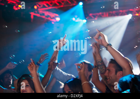 La folla entusiasta con le braccia sollevate sulla pista da ballo della discoteca Foto Stock