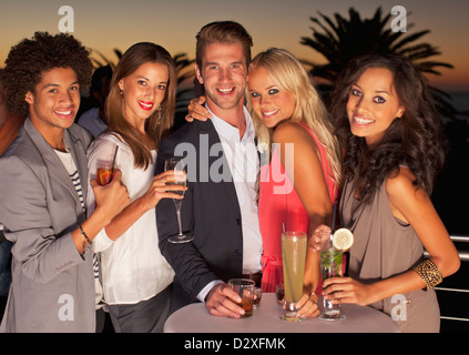 Ritratto di sorridere gli amici a bere un cocktail sul balcone al tramonto Foto Stock