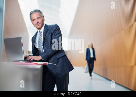 Ritratto di fiducioso uomo d affari con computer portatile in ufficio Foto Stock