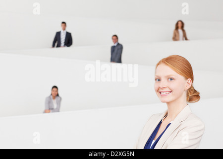 Ritratto di sorridere imprenditrice con co-lavoratori su scala in background Foto Stock