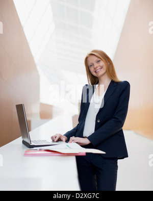 Ritratto di sorridere imprenditrice utilizzando computer portatile in ufficio Foto Stock